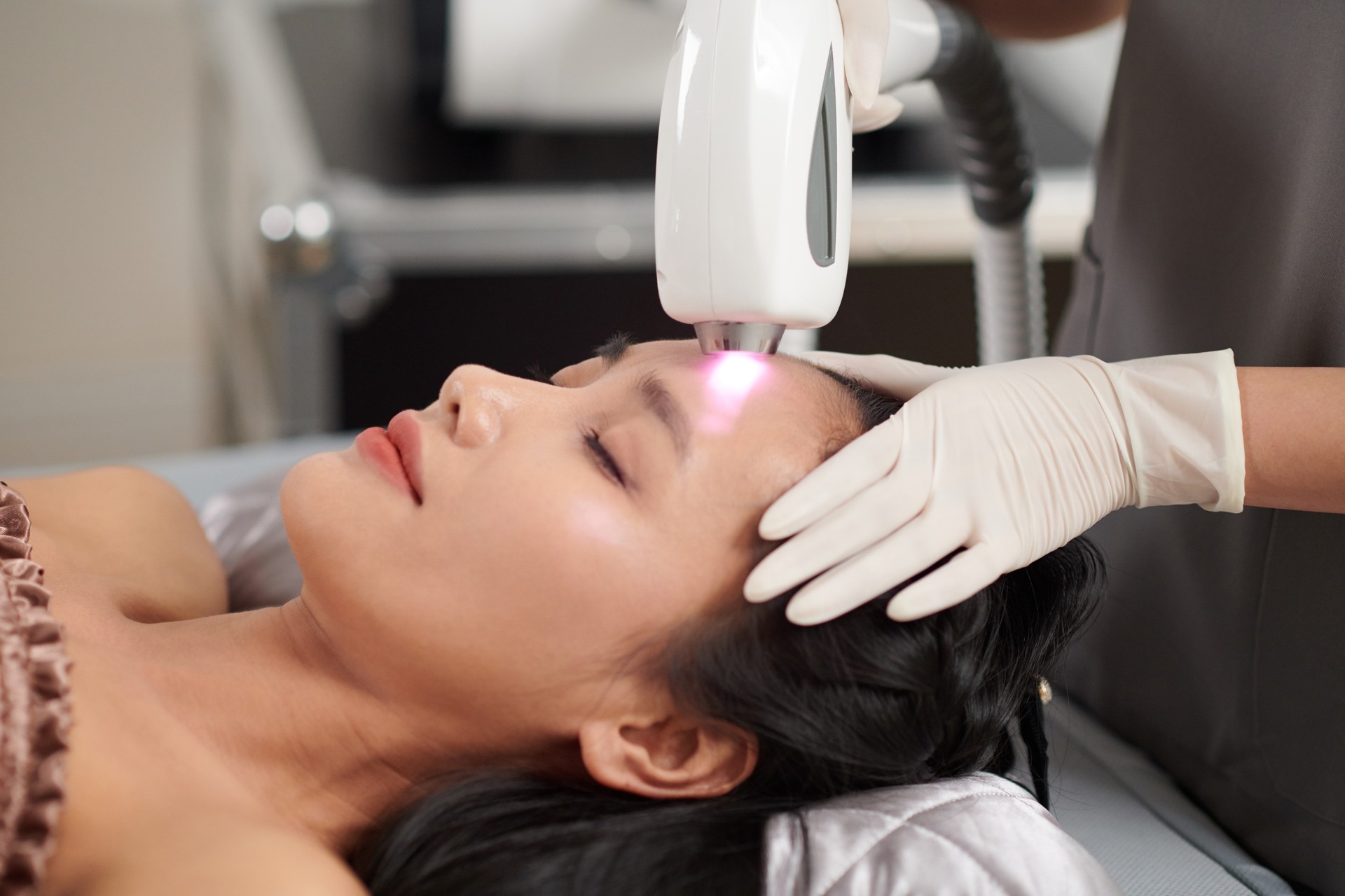 A professional performing IPL therapy on a patient’s face in a modern treatment room, with a focused light device and soothing ambiance.